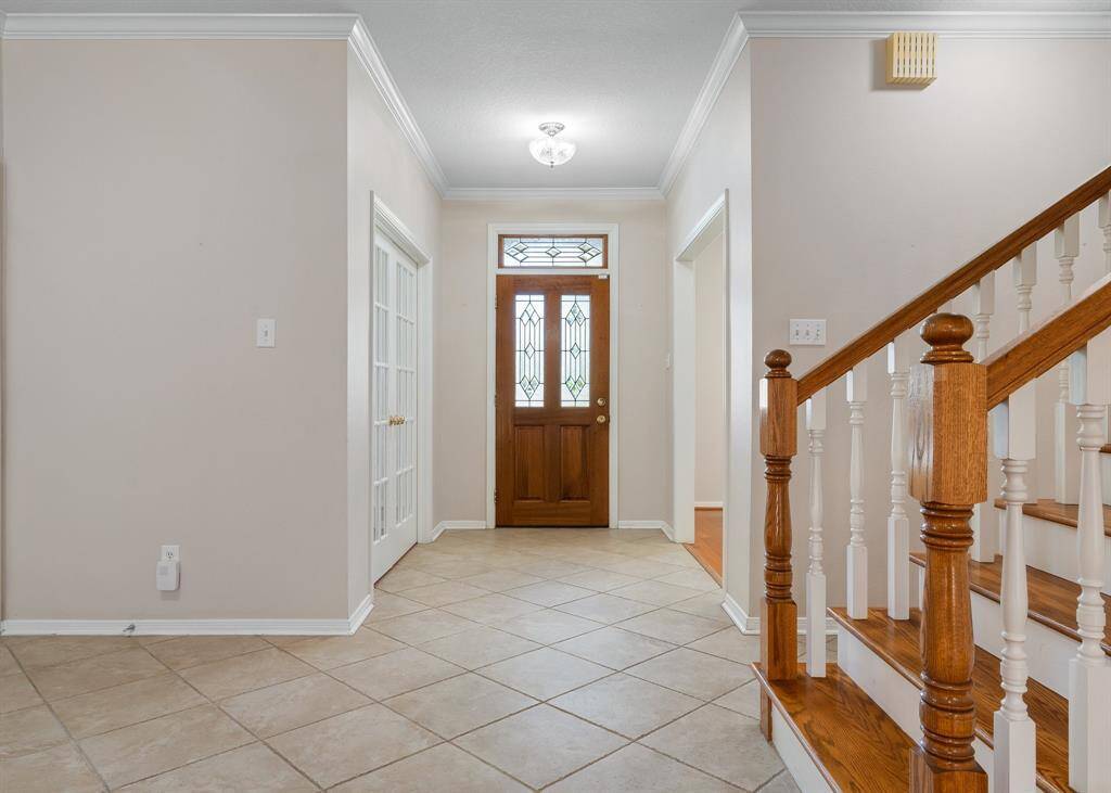 Upstairs staircase greets you upon entering the front door with wooden handrails and white spindles. A set of French doors leads to an adjacent study, adding elegance to the space.