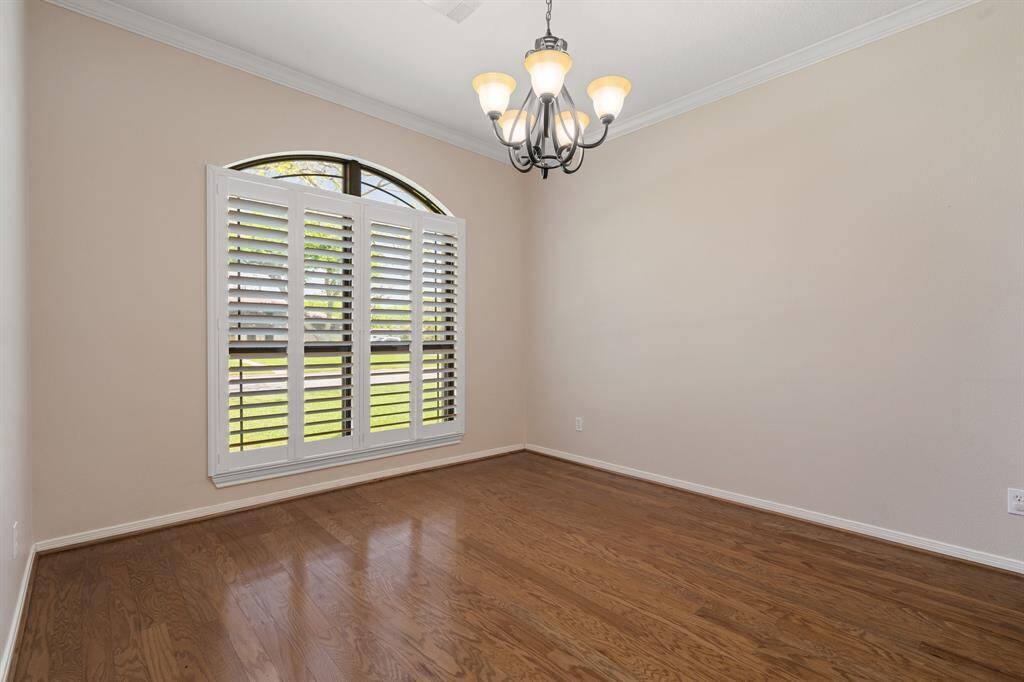 Formal dining room features hardwood flooring, a large window with elegant plantation shutters, and a stylish chandelier. Offering plenty of natural light and a cozy ambiance.