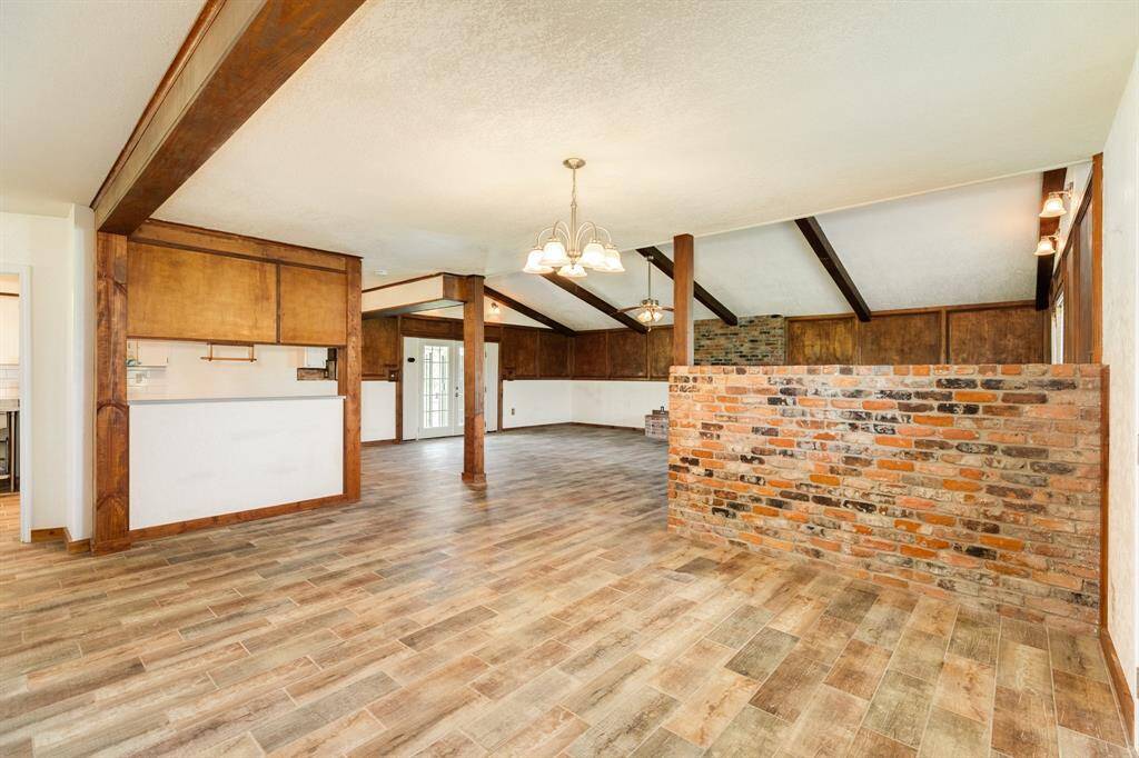 View of Dining Area toward Living Area. The wood-look tile flooring is just gorgeous, and the smart brick accent wall gives a bit of separation between the two spaces.