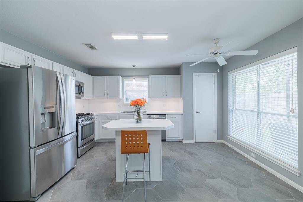 The kitchen boasts stainless steel appliances, a center island, gas cooking and under-cabinet lighting.