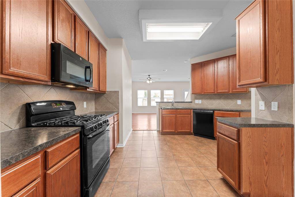 This spacious kitchen features a tiled backsplash, and modern appliances, including a gas stove and microwave.