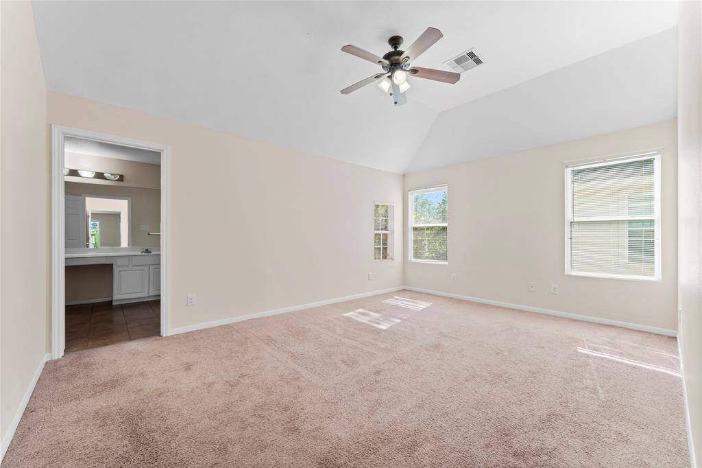 Spacious primary bedroom with neutral walls, a vaulted ceiling, and carpeted floor.