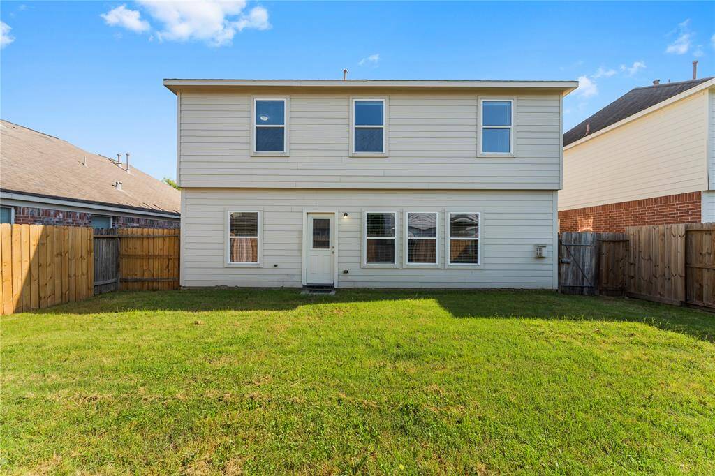 It features a simple exterior with multiple windows and a small, grassy lawn, perfect for outdoor activities.