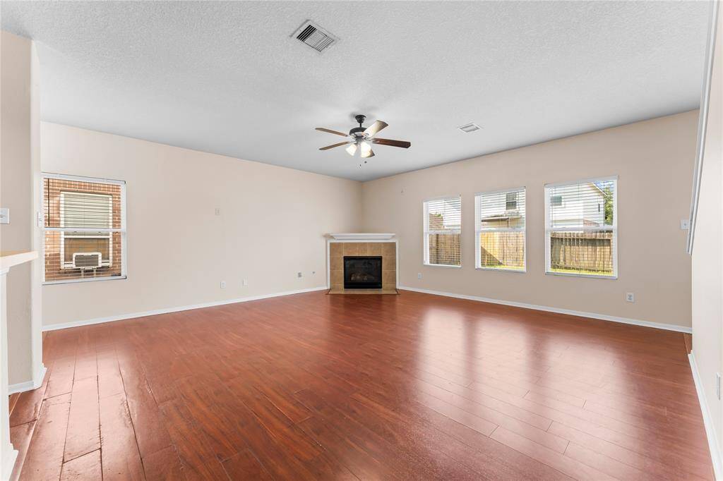 Spacious living room with a decorative corner fireplace, and abundant natural light from large windows.