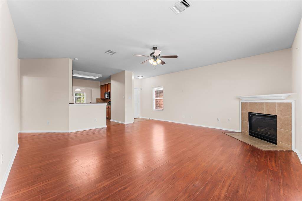 The open layout connects to a modern kitchen with wooden cabinetry, offering a warm and inviting atmosphere.