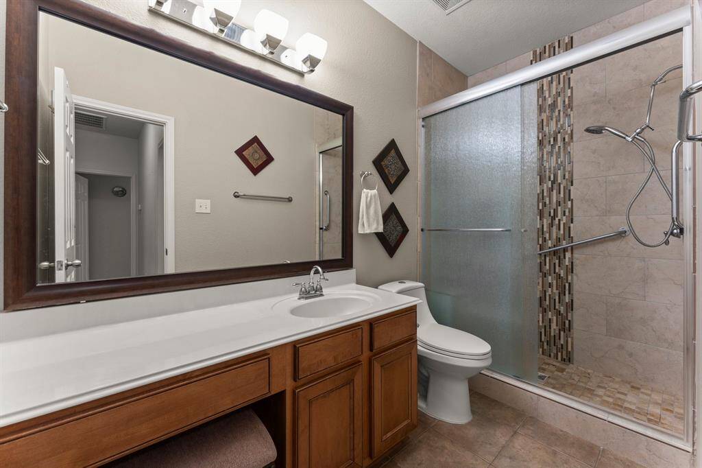 This well-appointed bathroom features a single sink, a large stand-up shower, and a separate vanity area, offering convenience and privacy for family members or guests.