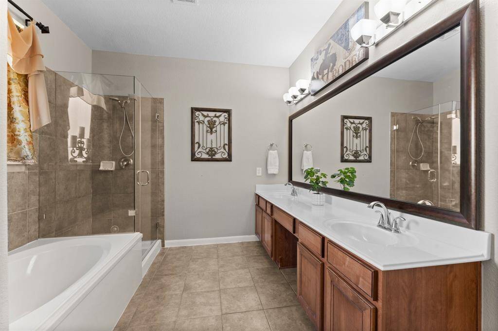 The spa-inspired primary bathroom features a soaking tub, a spacious walk-in shower with a seamless glass enclosure, and dual sinks with a dedicated vanity space for everyday luxury.