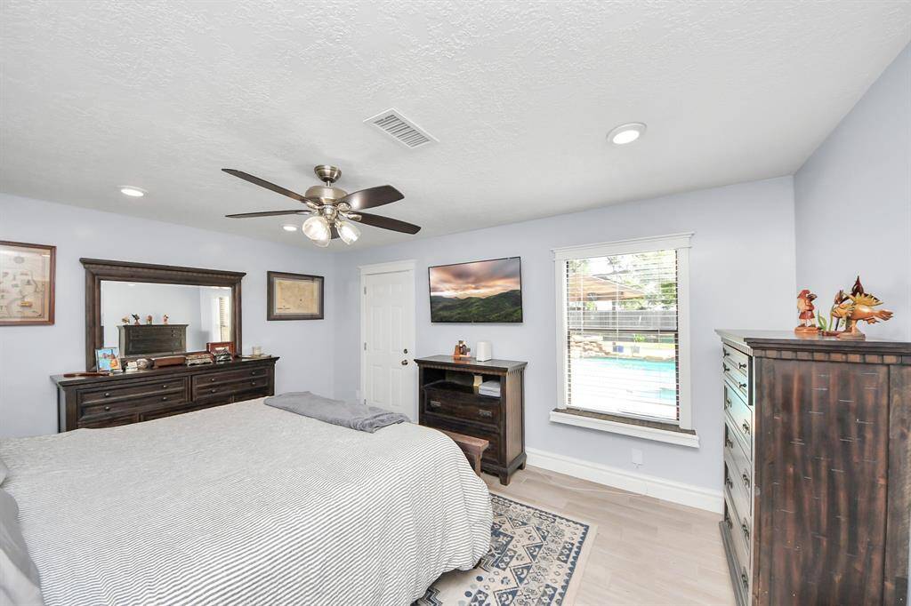 The private primary bedroom, located downstairs, is generously sized and offers a peaceful retreat. Featuring warm wood laminate flooring and a private door leading to the backyard, this space combines comfort and convenience with direct access to your outdoor escape.