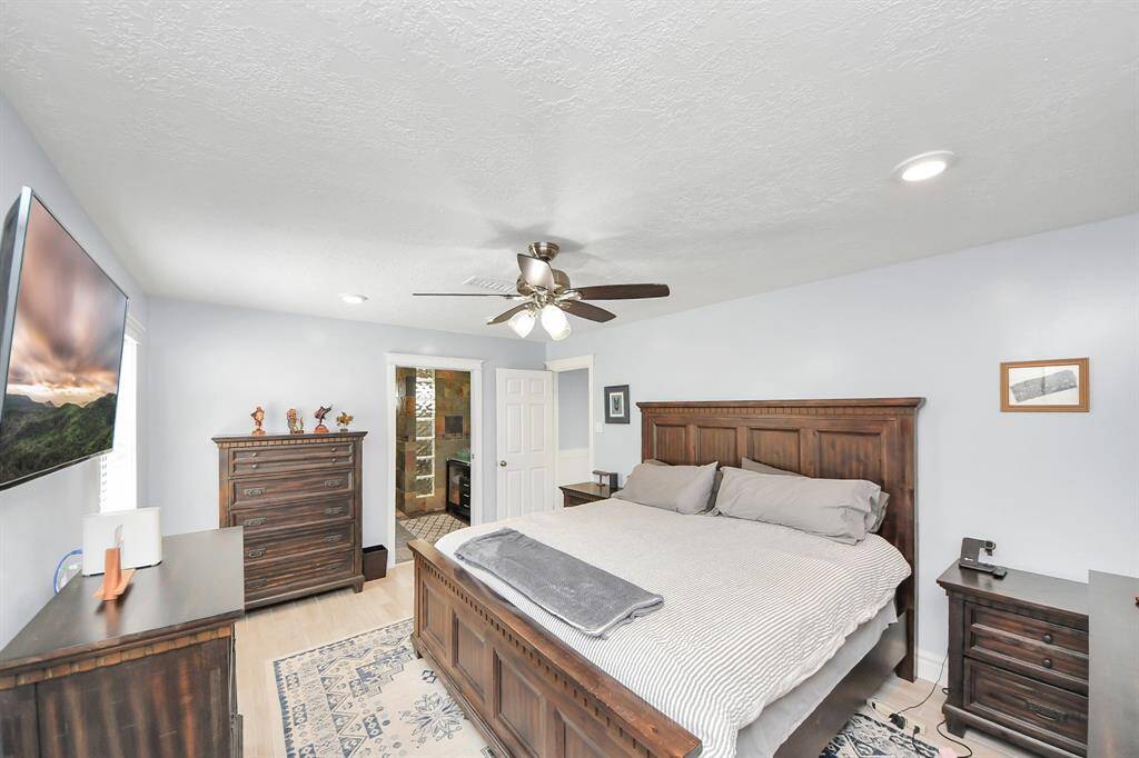 The expansive owner's suite easily accommodates large furnishings, offering plenty of space to create a luxurious and functional retreat. Graced with low-maintenance wood tile flooring, this room combines elegance with practicality.