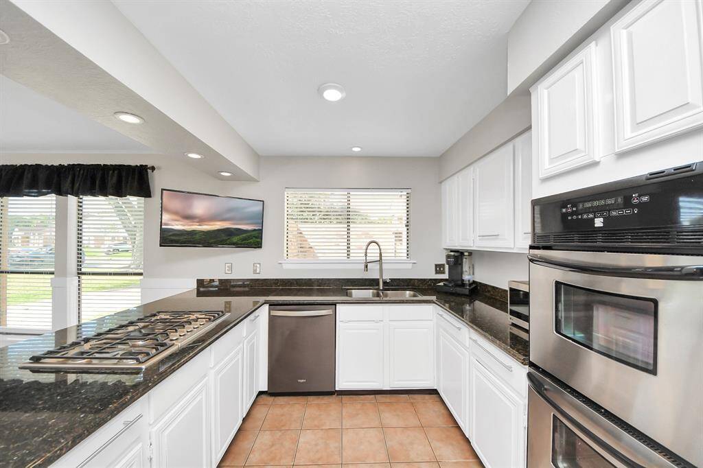 The kitchen area showcases striking dark granite countertops that beautifully complement the crisp white cabinetry.