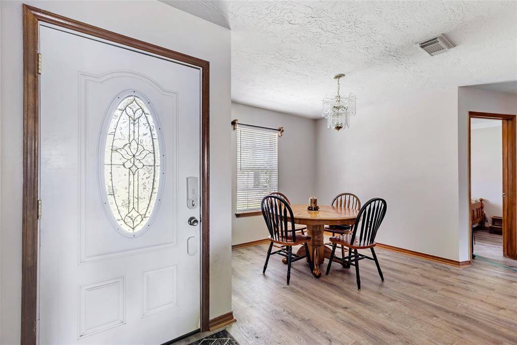 This photo shows a bright entryway with a decorative front door. Turn left into a dining space  that has a window letting in natural light.