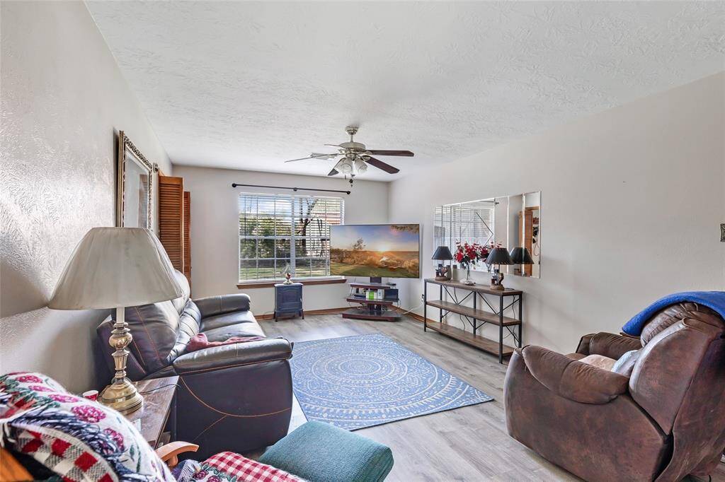 This inviting living room features a large window providing ample natural light, a ceiling fan for comfort creating a welcoming atmosphere.