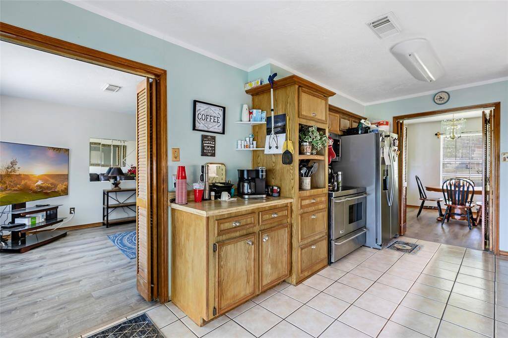 This kitchen features classic wooden cabinetry, a stainless-steel dishwasher, and a spacious countertop.  A dining area is visible through the doorway, adding convenience for meals.