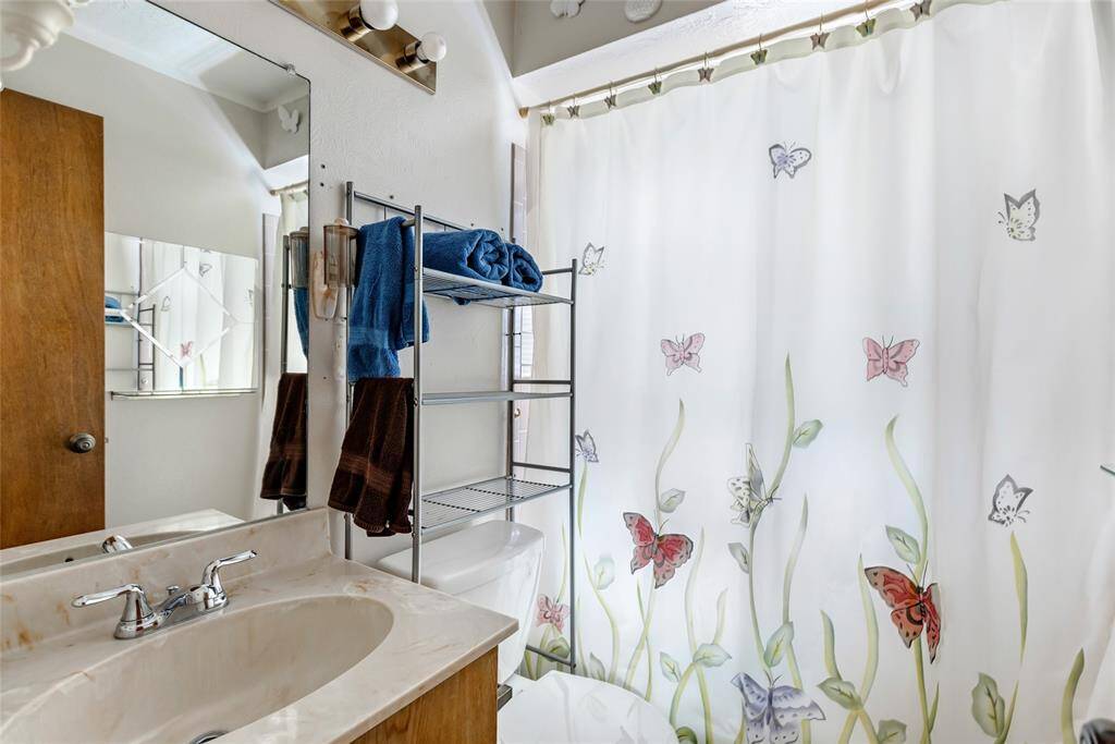 This third bedroom features a large window, allowing plenty of natural light. It has a ceiling fan, neutral walls, woodgrain flooring.