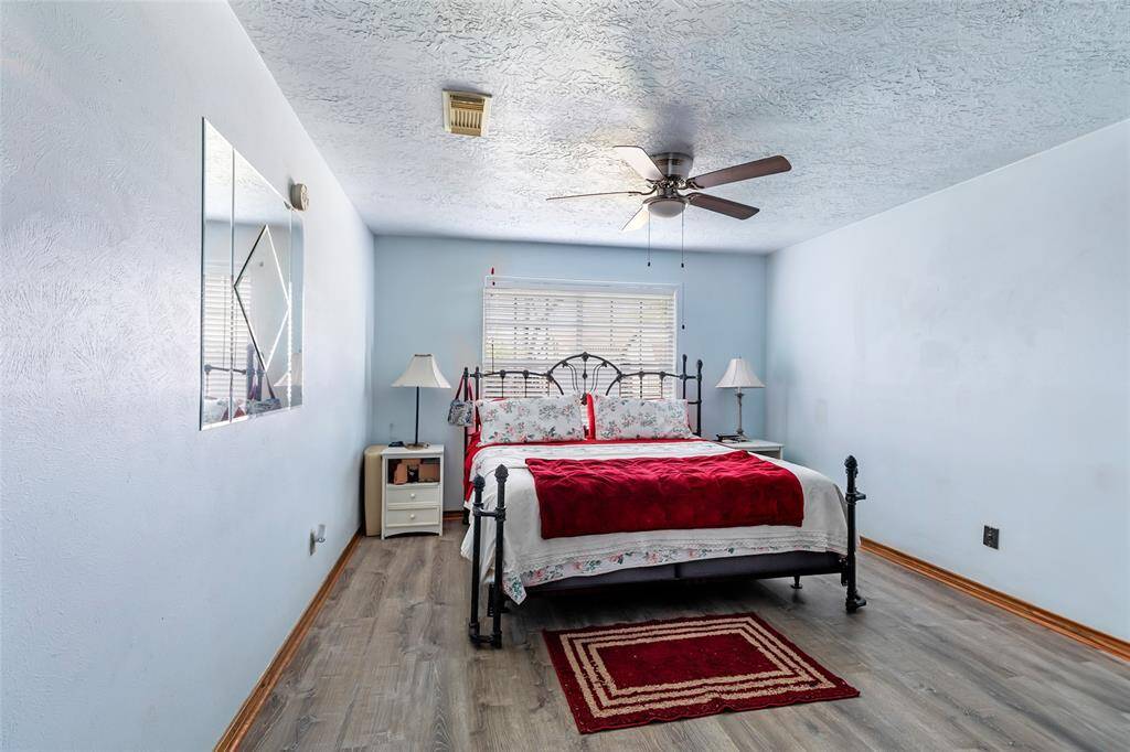 Another bedroom with neutral walls and wood-look flooring, featuring a window that lets in natural light. There's a ceiling fan for comfort.