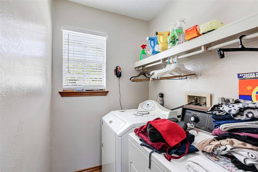 This laundry room features shelving for storage, and a window for natural light, offering a functional and organized space for laundry tasks.
