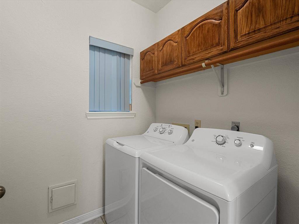 Dedicated laundry room with washer, dryer, and overhead storage cabinetry.