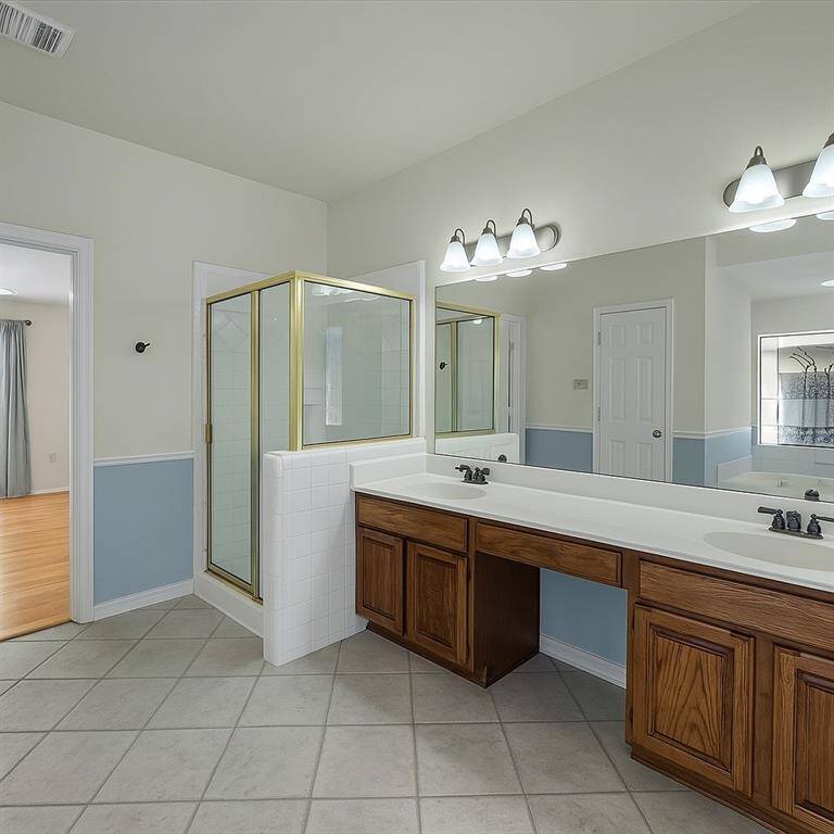 Large dual vanity with expansive mirror, plus private shower and soaking tub.