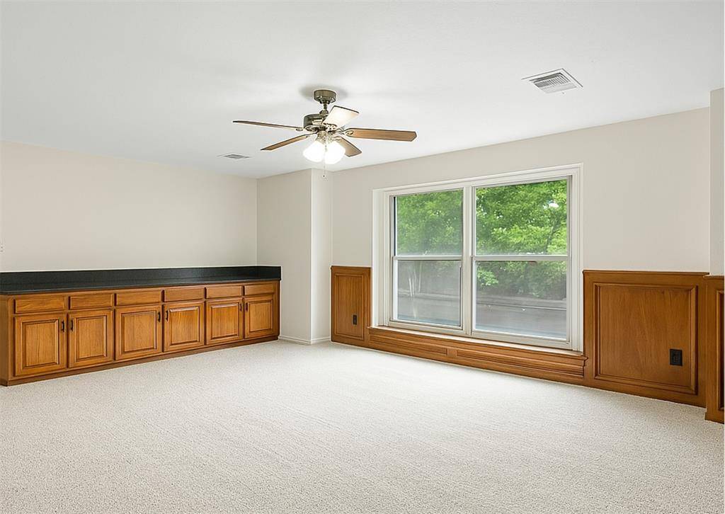 Game room features dual ceiling fans, wainscoting, and new carpet—ready for movie nights or home gym.