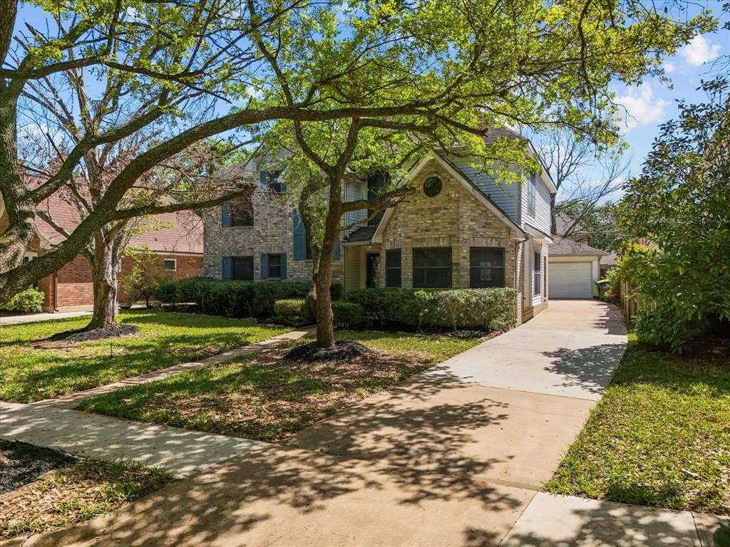 Beautiful two-story brick home with shaded walkway and long driveway to detached garage.