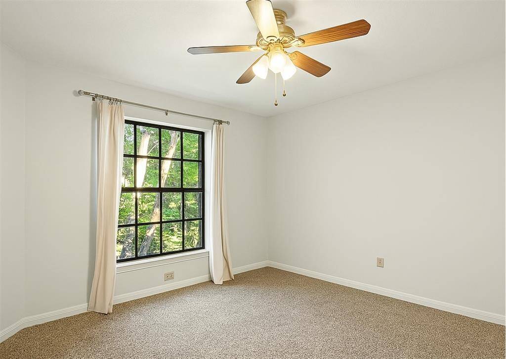Third upstairs bedroom featuring plush carpet, large window, and ceiling fan.