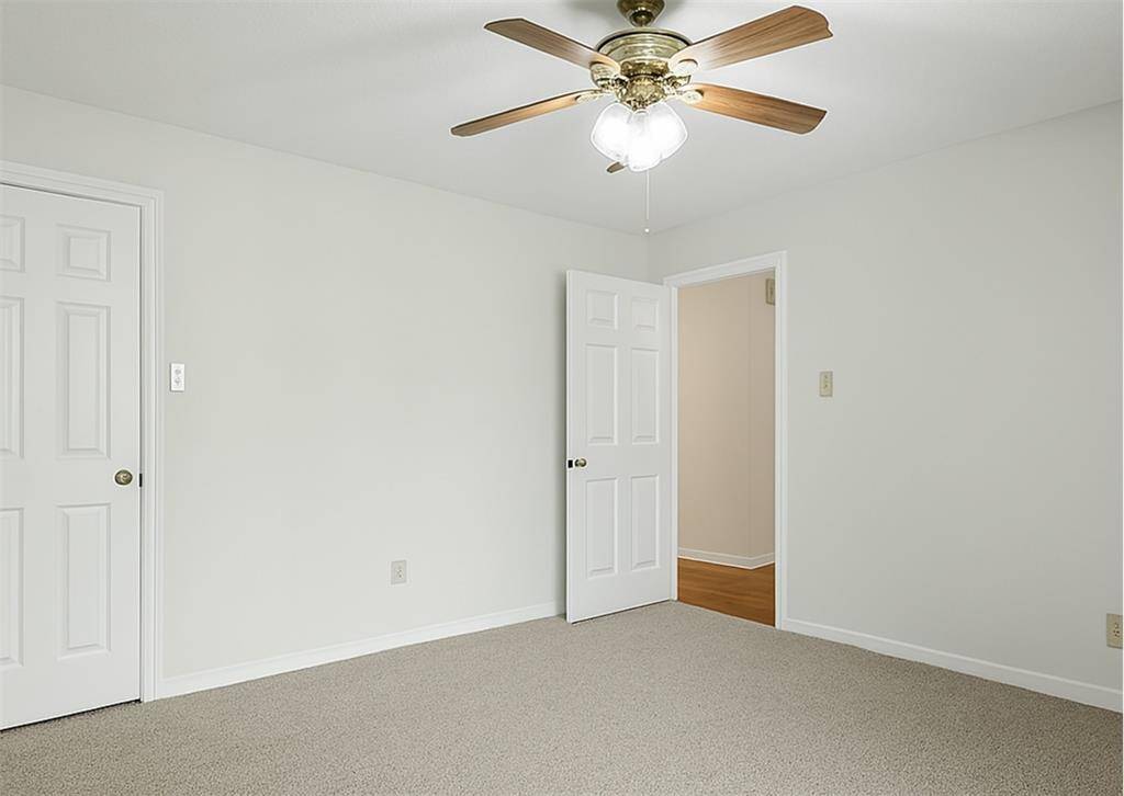 Upstairs bedroom with fresh carpet, ceiling fan, and walk-in closet.