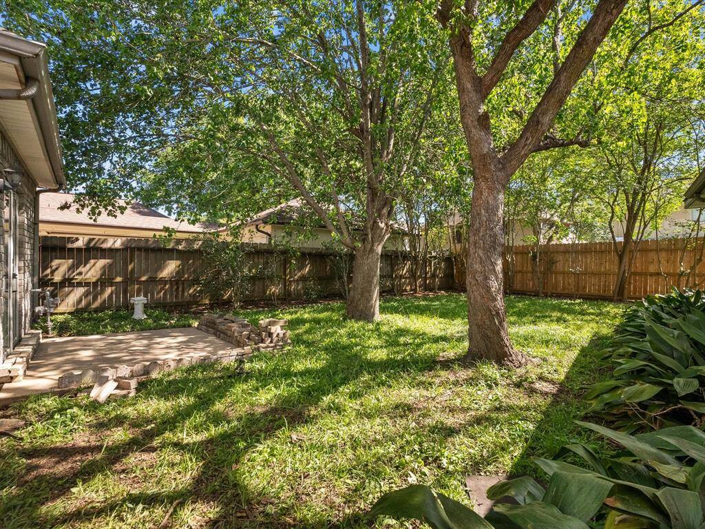 Peaceful, tree-lined backyard with fully fenced perimeter and shady retreat vibes.