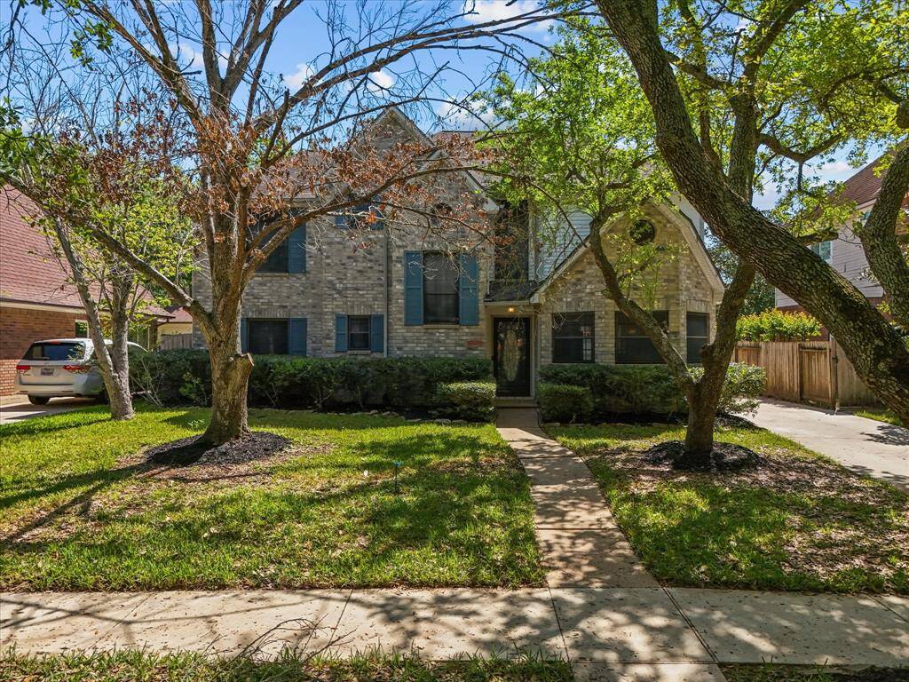 Picturesque front yard framed by mature trees and a welcoming path to the front door.