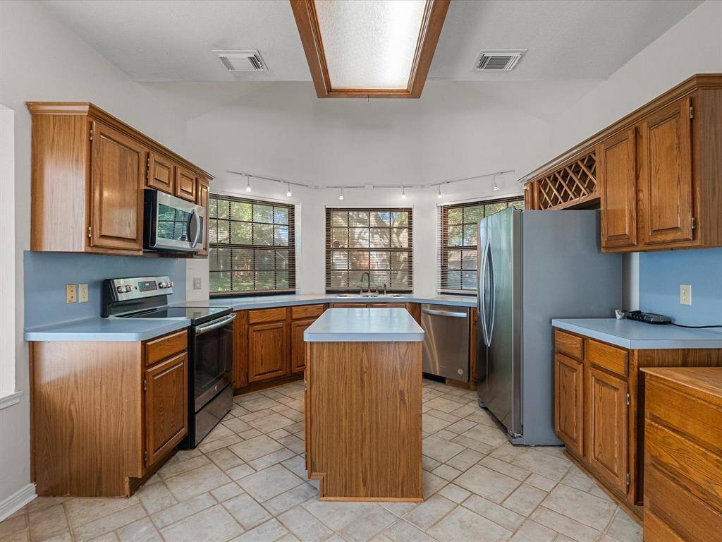 Well-maintained kitchen with island, stainless appliances, bay windows, and ample cabinetry.