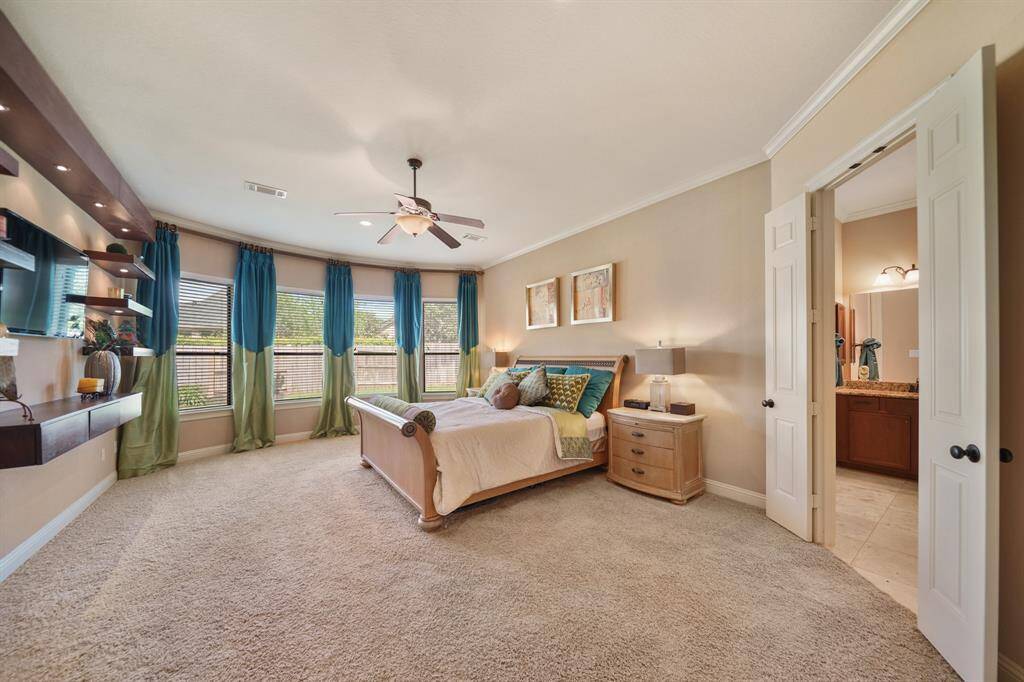 Spacious, inviting primary bedroom with large windows, plenty of natural light, and elegant decor and an adjoining bathroom.