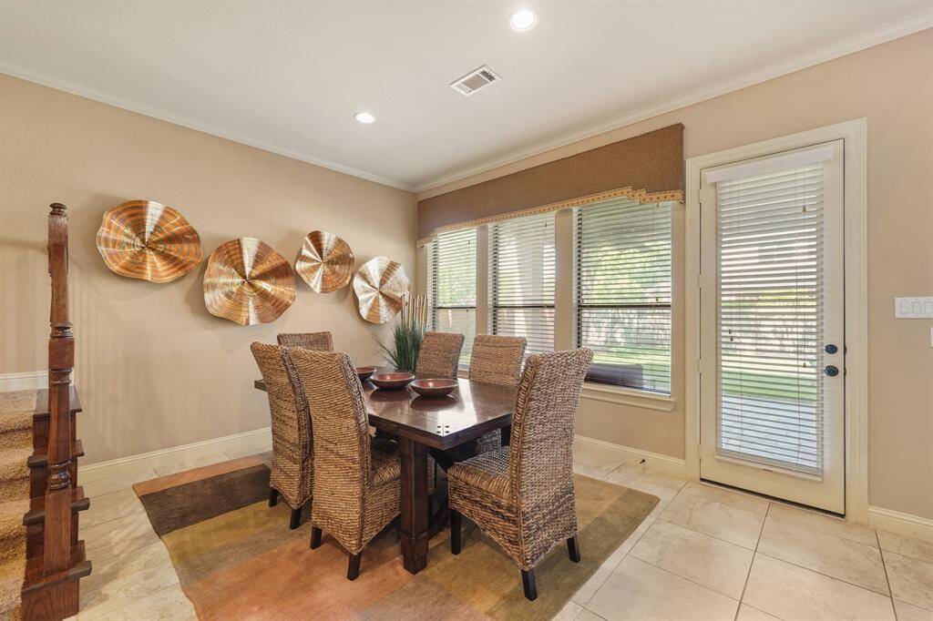 This dining area features a warm, inviting atmosphere with natural light from large windows. The room has a neutral palette and a door leading to the outdoors.