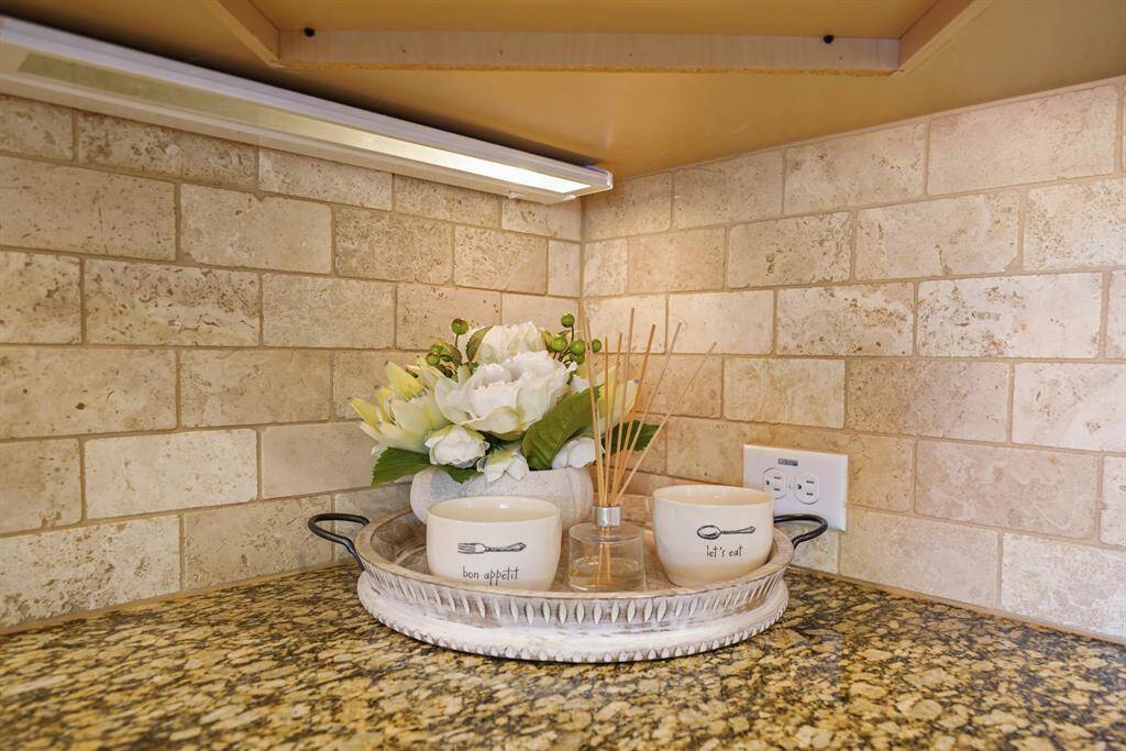 This kitchen corner features a granite countertop and neutral tile backsplash.
