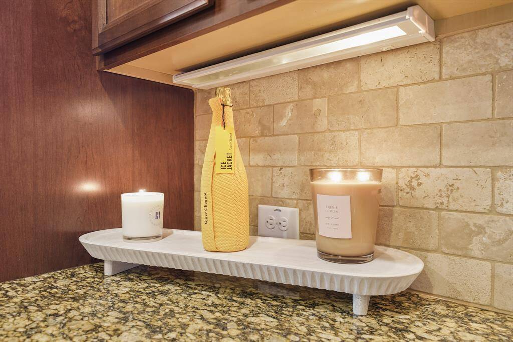 This kitchen features a cozy, elegant corner with a granite countertop, warm-toned tile backsplash, and under-cabinet lighting.