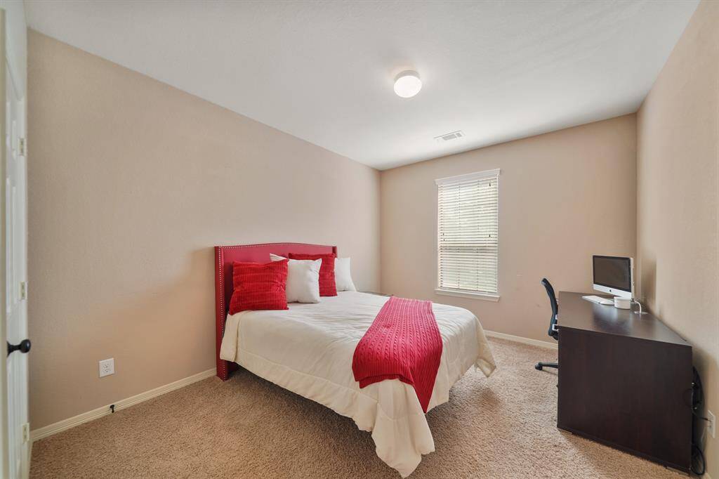 This cozy bedroom features neutral walls, carpeted flooring, and a window providing natural light. I