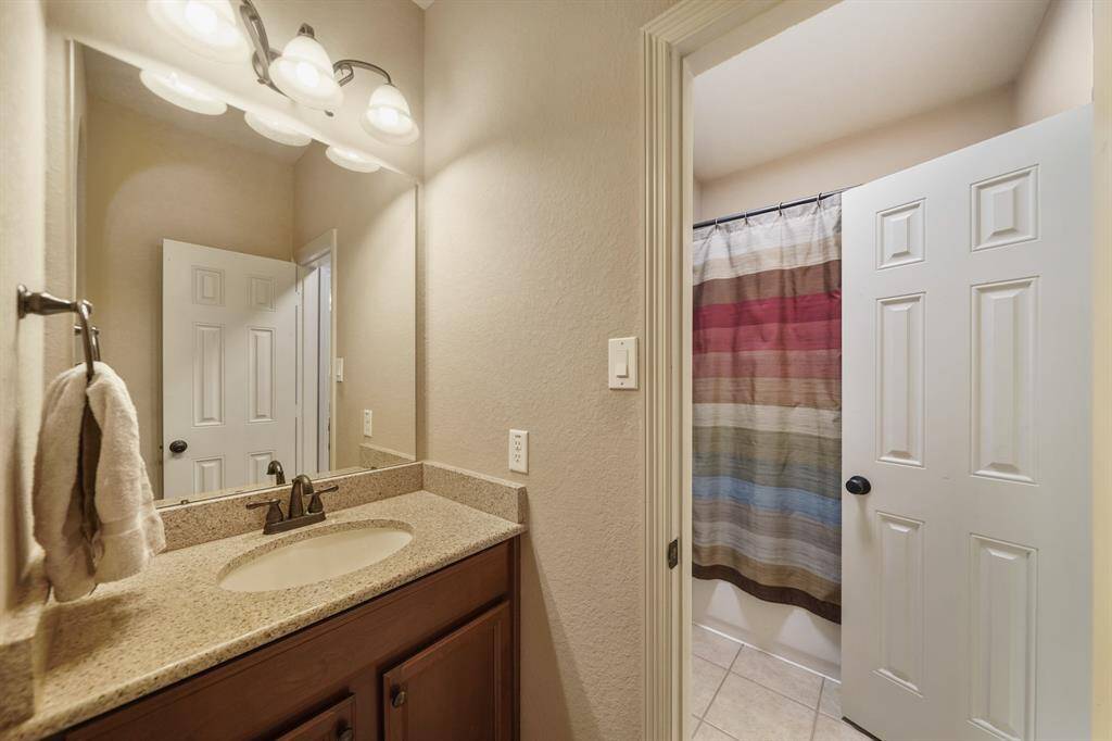 This bathroom features a granite countertop with a single sink, under-cabinet storage, and a large mirror.