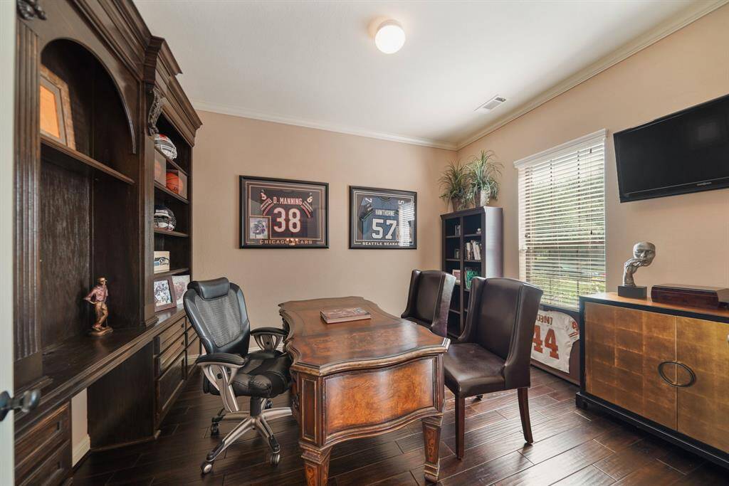 This home office features elegant wood flooring, built-in shelving, and a large window for natural light.