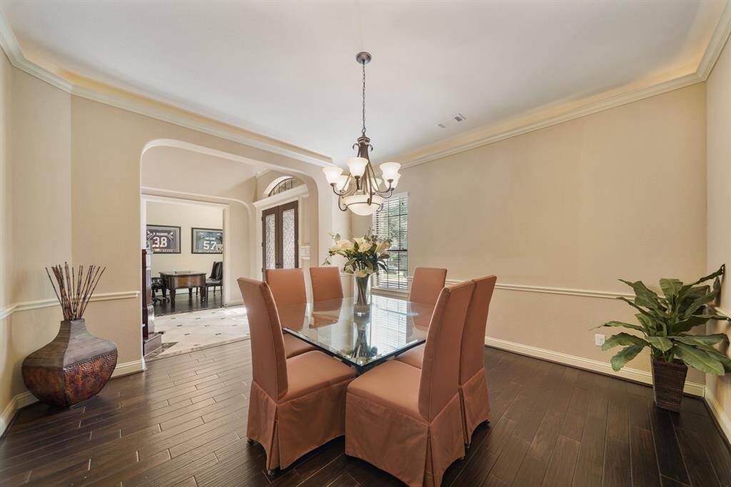 This elegant dining room features dark wood flooring, large windows and archways create an open, inviting atmosphere.