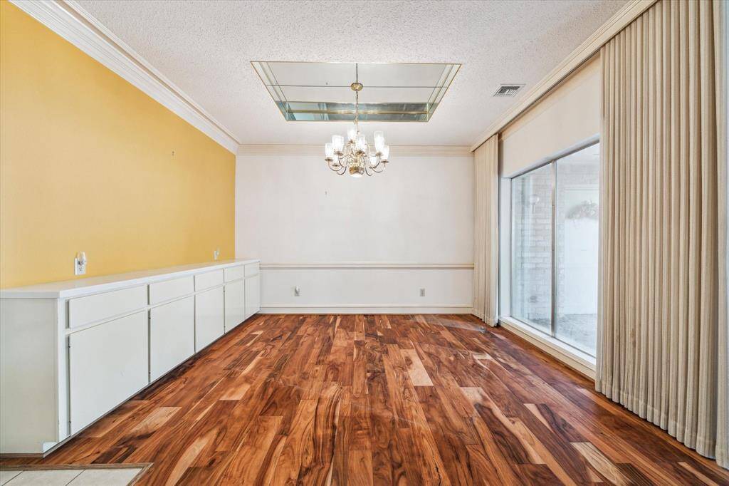 The dining room features warm wood flooring and a large window with vertical blinds.  The space spills out to the outdoor entertaing area where you will find a gas grill that is connected and will remain with the home. It has a yellow accent wall with cabinets for all your dining needs and storage. The mirrored ceiling adds an elegant feel with the chandelier reflection.