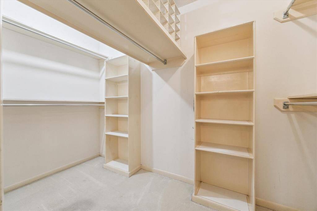 This photo shows a spacious walk-in closet with built-in shelves and ample hanging space, ideal for organizing clothes and accessories.