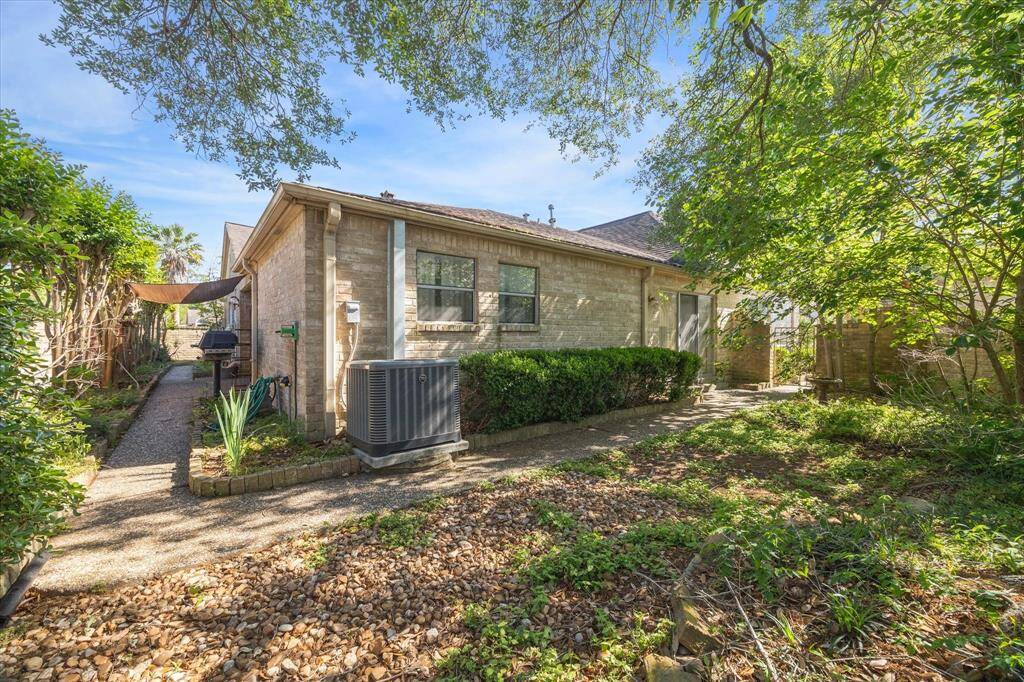 Showcasing the large backyard just outside your primary suite.  It features a well-maintained garden with mature trees and shrubs. A paved pathway leads alongside the house, offering a serene outdoor space.