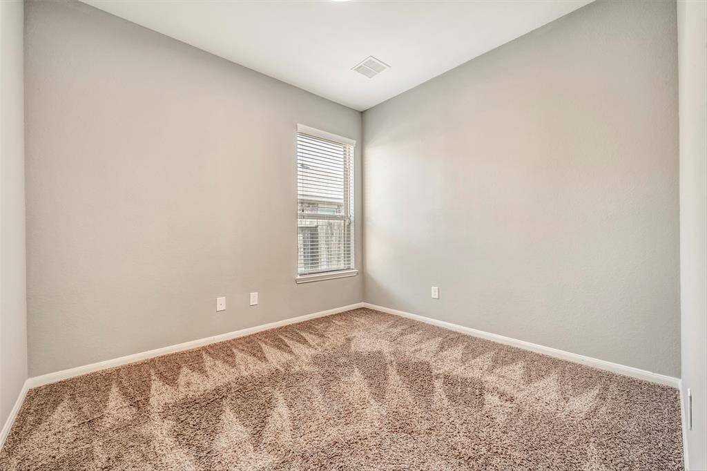 This is a small, carpeted room with neutral-colored walls and a single window, providing natural light. Ideal for use as a playroom or home office.