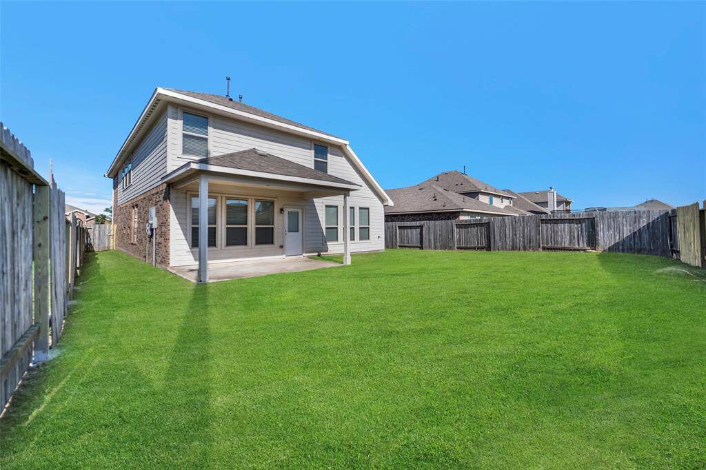 Spacious backyard view showcasing the home's inviting patio and privacy with fenced surroundings.