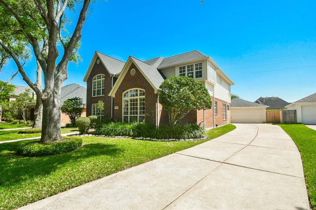 Spacious double-wide driveway leads to a detached two-car garage.