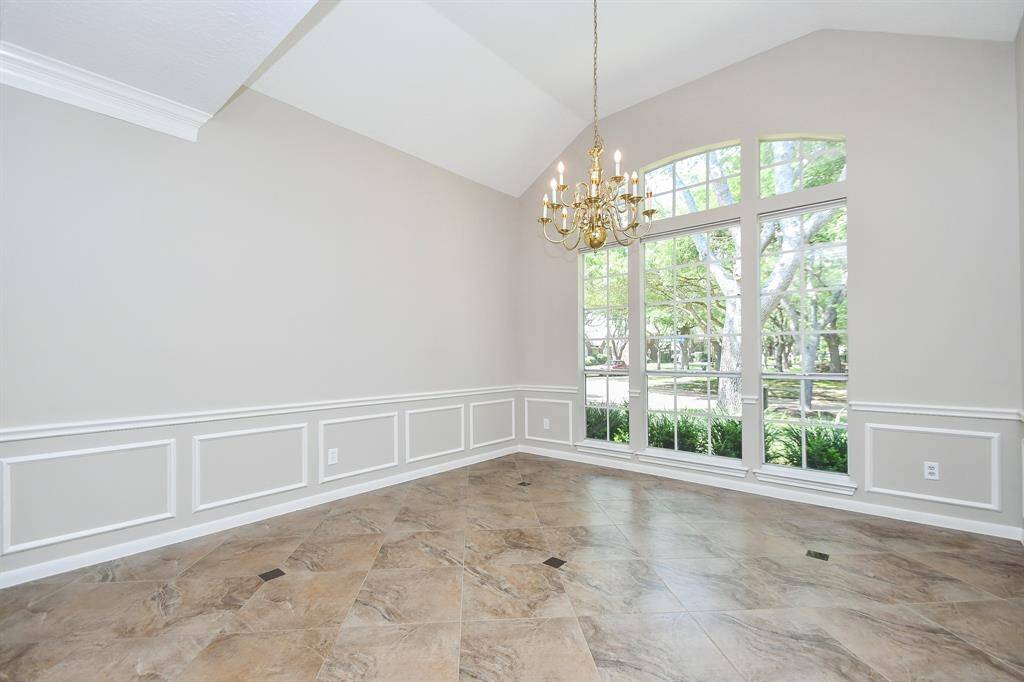 Elegant dining room with expansive windows, classic wainscoting, and a stunning chandelier—perfect for memorable gatherings.
