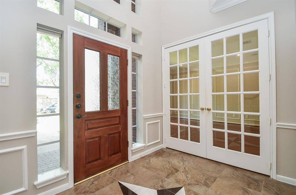 Welcoming entryway with a spacious study behind elegant French doors on the left.