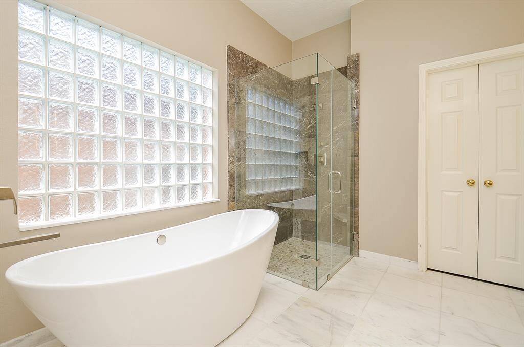 Beautifully updated en suite primary bath with soaking tub and glass shower
