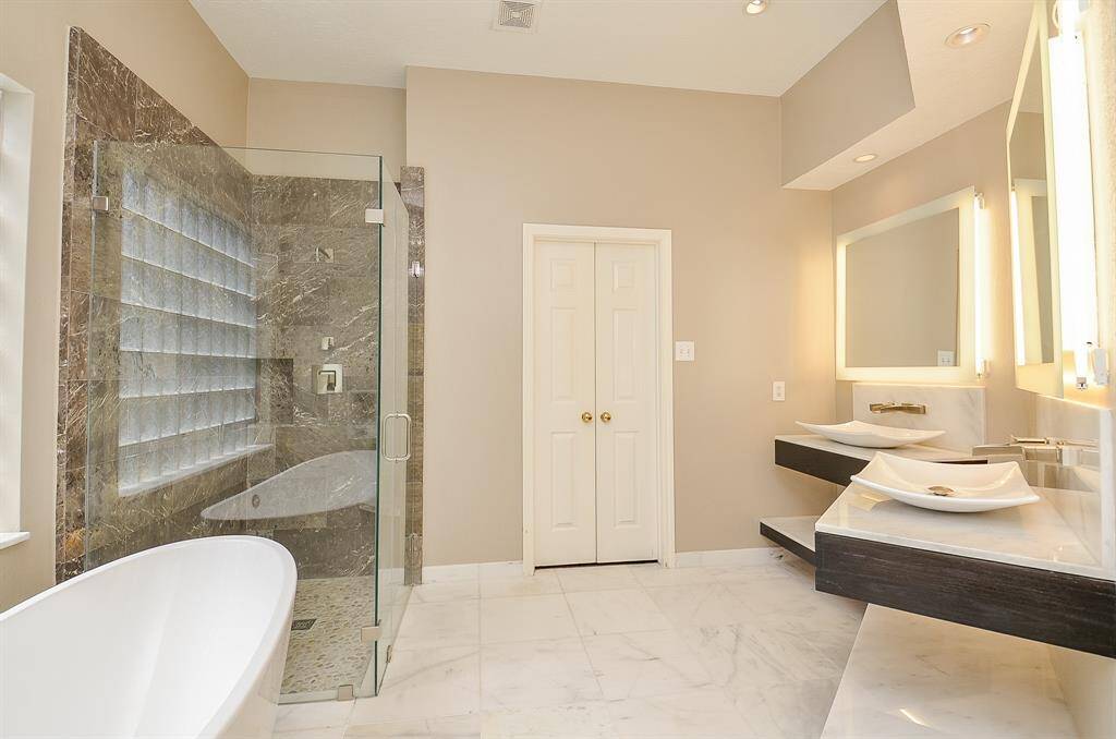 Another view of the primary en suite- separate sinks, lighted mirrors and large walk in closet plus linen closet (not visible in the photo)