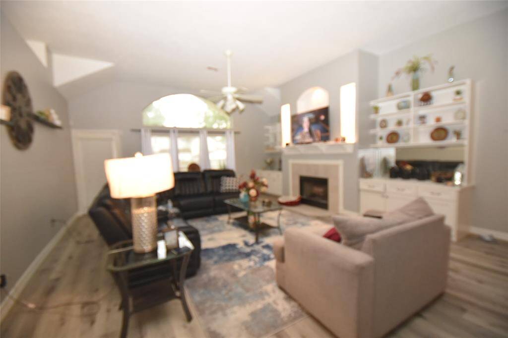 The spacious family room is nestled in the center of the homeStep into the heart of the home, where the inviting family room awaits. This expansive space boasts a charming wood-burning fireplace, perfectly framed by built-in shelving and cabinets that provide ample storage. The elegant wood flooring adds a touch of warmth and sophistication, making it the ideal place for family gatherings and cozy evenings.. It features a wood-burning fireplace surrounded by built-in shelving and cabinets for additional sto