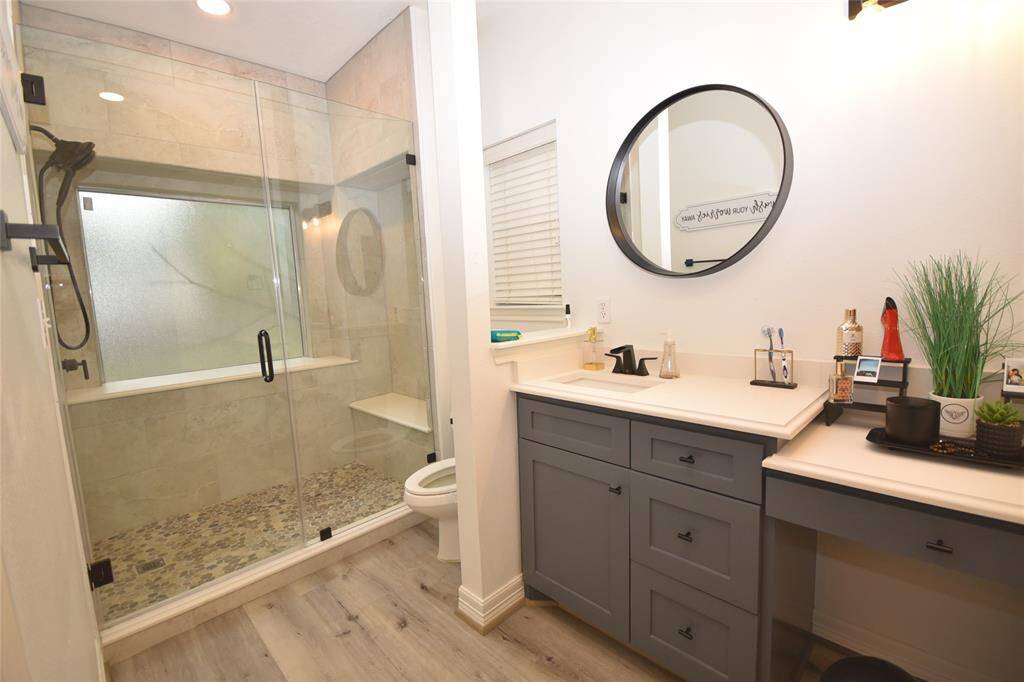 The primary bathroom offers a sizeable walk-in shower. Ample bench seating invites you to unwind, whether you’re enjoying a soothing rainfall showerhead or a quick rinse after a long day. A privacy window lets in soft natural light, brightening the space while maintaining seclusion. This large shower transforms daily routines into a spa-like retreat, making it a truly inviting spot to refresh and rejuvenate.