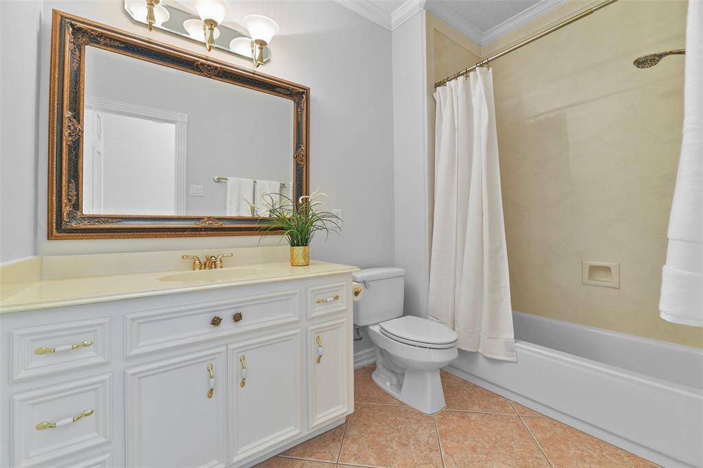 This full bathroom is located on the first floor and it boasts a cultured marble countertop with a basin sink, freshly painted white cabinetry, a framed mirror, sconce lighting, tile floors, and a combination bathtub and shower with a cultured marble surround.